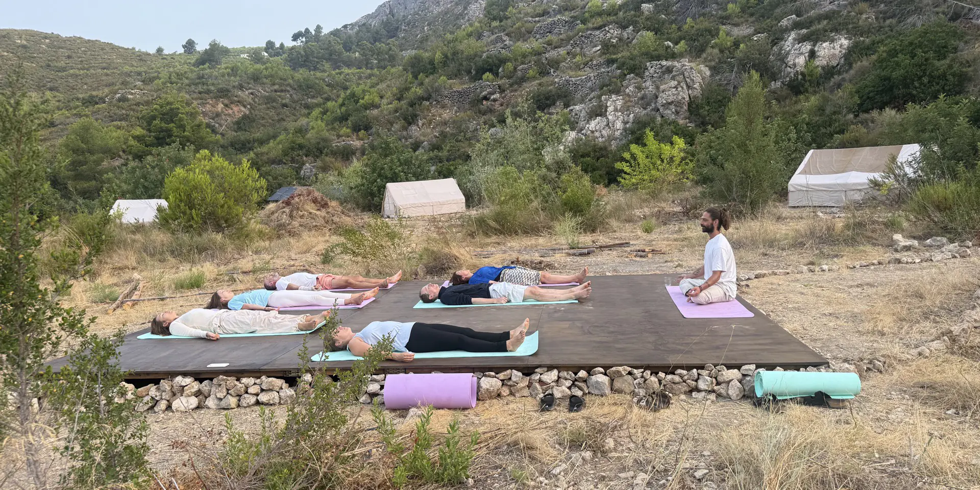 A group practising yoga beneath the Himalayan mountains.