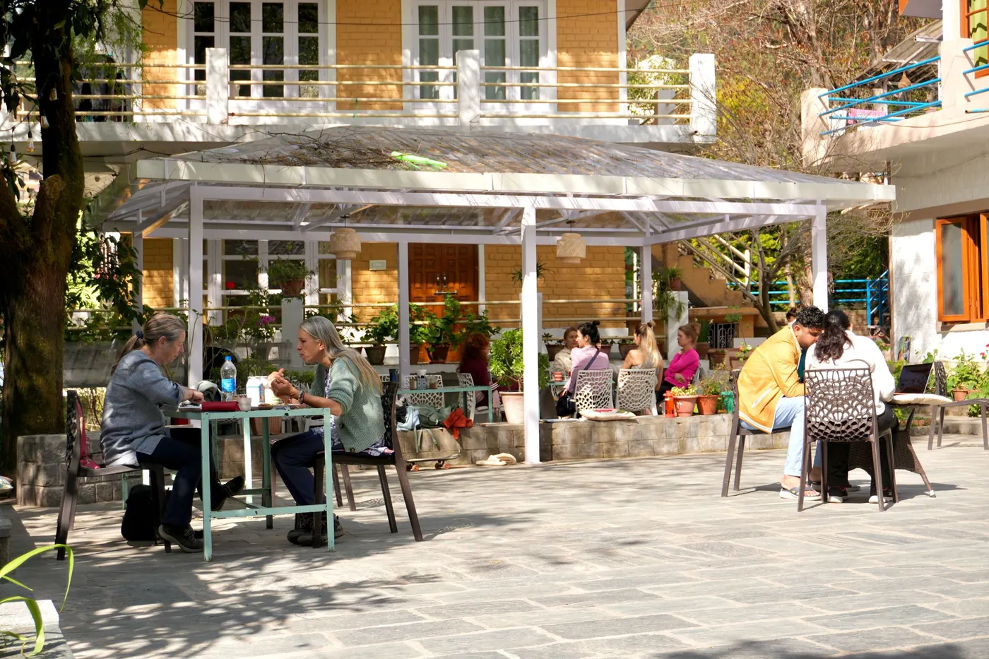 Guests gathering around outdoor tables in the Trimurti courtyard.