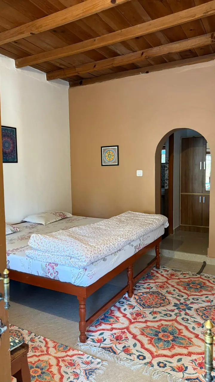 Twin room at Trimurti with light bedding and an arched doorway.