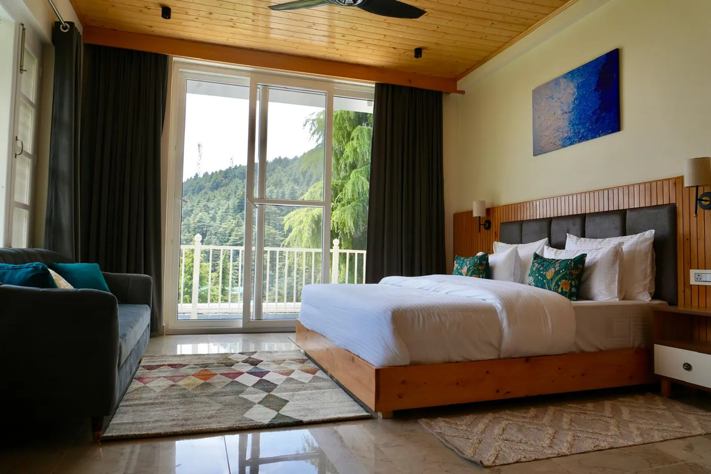 Bright guest room at Trimurti with a balcony and Himalayan forest view.