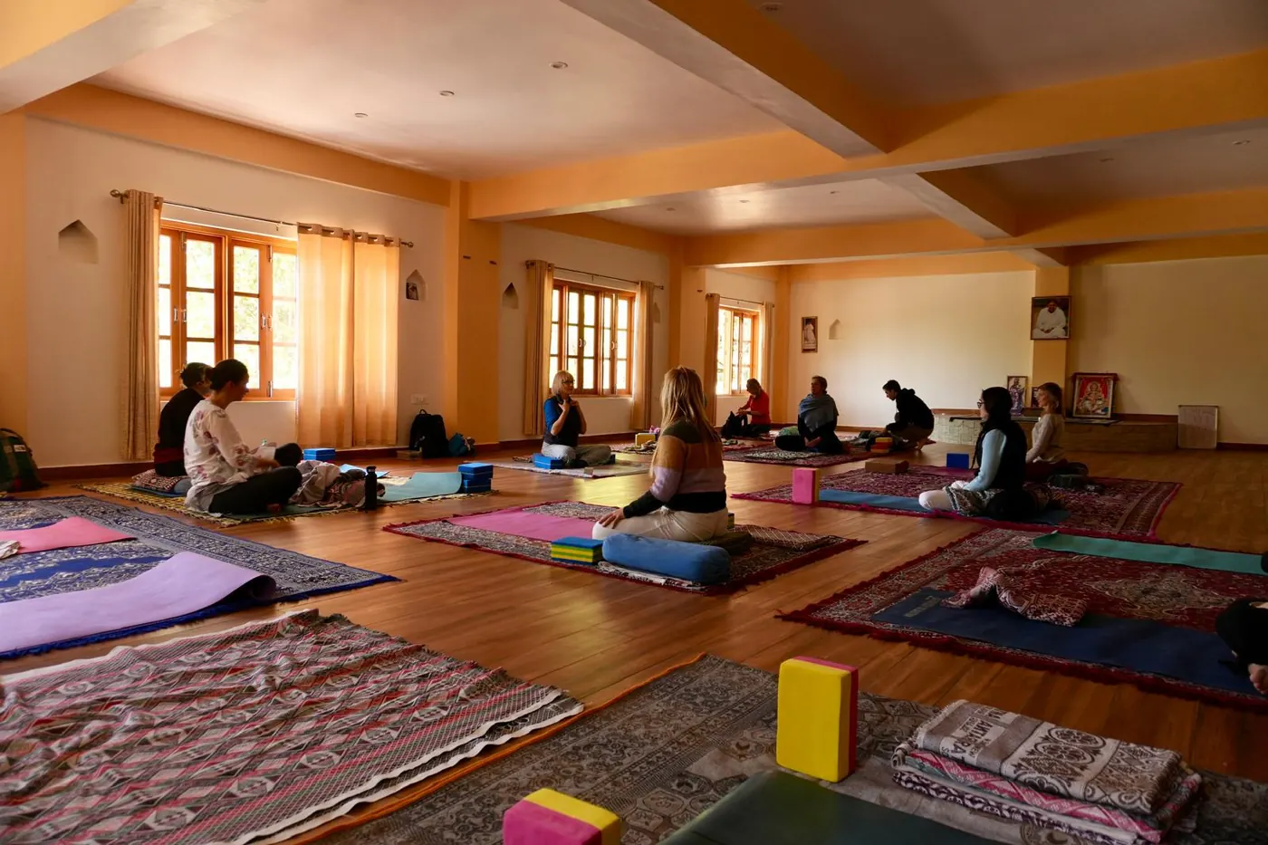 Yoga practice hall at Trimurti prepared with mats and meditation cushions.